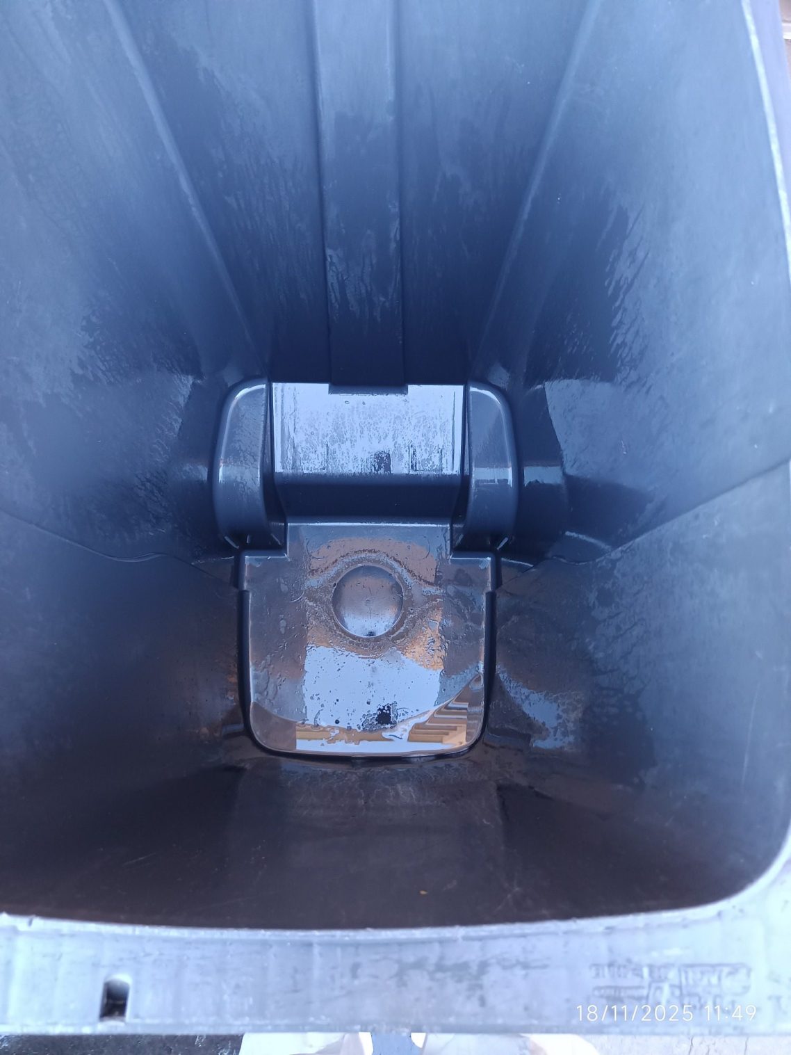 Intérieur d'une benne à ordures, vide et en plastique, montrant le fond et les parois.